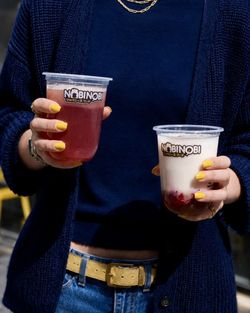 Deux bubble teas aux saveurs différentes tenus par une personne au restaurant Nobi Nobi Pessac.