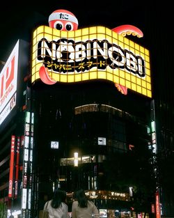 Enseigne lumineuse du restaurant asiatique Nobi Nobi représentant une pieuvre dans une rue animée la nuit.
