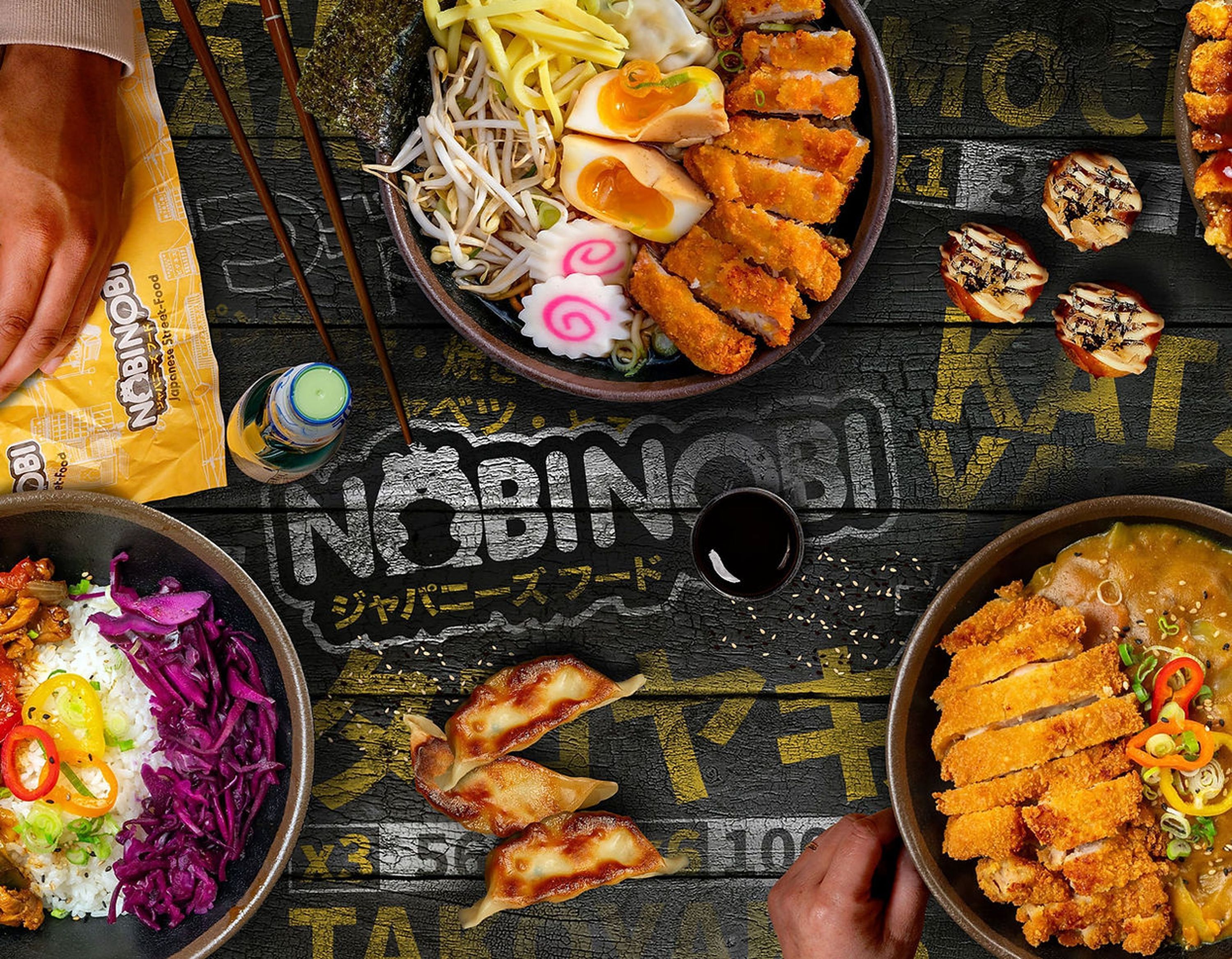 Plats asiatiques variés incluant ramen, gyozas, riz et légumes colorés sur une table avec logo Nobi Nobi.